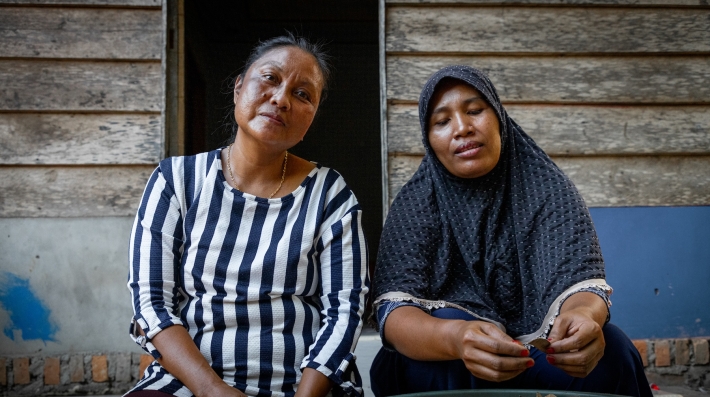 Two women collecting acacia seeds for a paper plantation near Siak in central Sumatra, Indonesia, sit side by side 