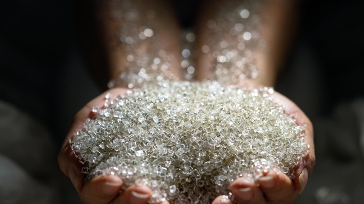 Clear plastic pellets from ocean waste in human hands.