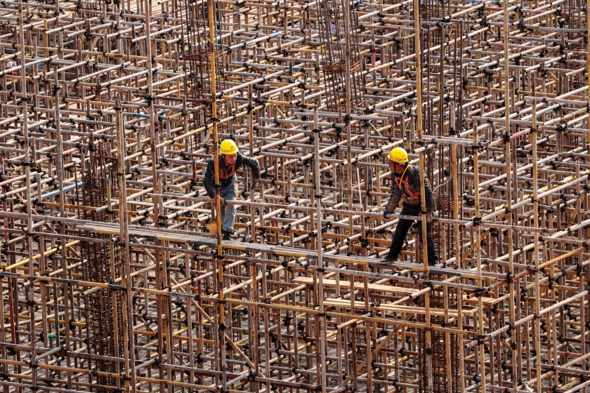 Two workers on a construction site surrounded by scaffoldin