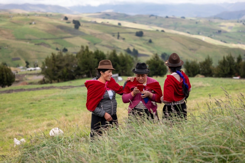 Three women chatting, with the peaks of the Andes in the background.